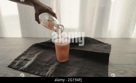 homme servant une boisson pétillante rose dans un verre à gobelet avec morceau de glace, grande photo Banque D'Images