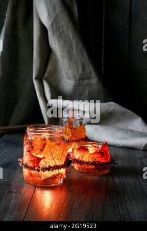 Lanterne d'automne faite d'un pot en verre décoré de feuilles colorées et d'une couronne de bruyère. Bougie à l'intérieur. Banque D'Images