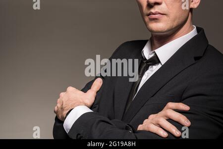 Homme d'affaires aux armes croisées. Costume moderne et sûr pour jeune homme gros plan. Banque D'Images