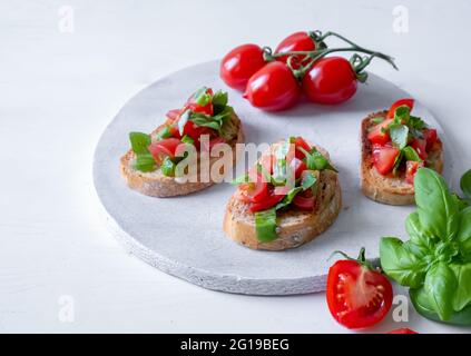 Trois bruschetta aux tomates et basilic frais sur un panneau en bois blanc Banque D'Images