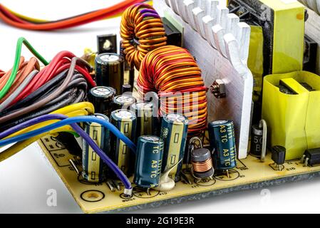 Bobine d'induction, bobine toroïdale sur un anneau avec hélice en cuivre visible et condensateurs, montés sur une carte de circuit imprimé dans une alimentation d'ordinateur. Banque D'Images