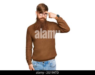 Jeune irlandais redhead homme portant des vêtements et des lunettes décontractés pointant malheureux à pipple sur le front, infection laid de la tête noire. Acné et problème de peau Banque D'Images