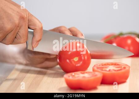 Femme coupant de la tomate fraîche: Foyer sélectif. Concept d'alimentation et d'alimentation saine Banque D'Images