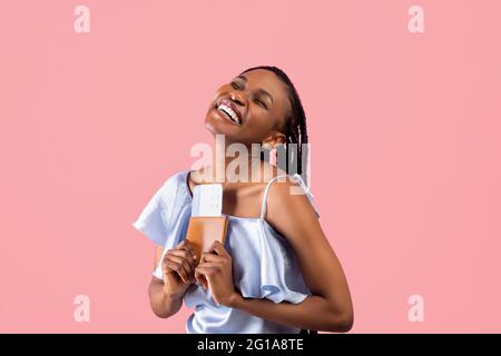 Jeune femme noire se sentant heureuse, avec passeport et billets d'avion, en vacances d'été, en voyage dans le monde entier Banque D'Images