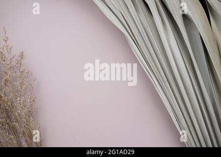 Les feuilles de palmier sèches et le bouquet de fleurs sauvages flétrissent sur fond gris-violet argenté neutre. Banque D'Images