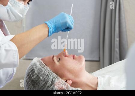 le cosmétologue applique de l'huile au visage du client dans le salon de beauté Banque D'Images