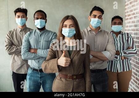 Hommes d'affaires multiculturels dans des masques debout au bureau avec les bras pliés Banque D'Images