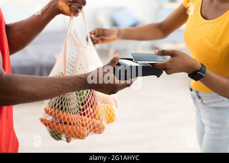 Femme africaine qui paie pour ses courses reçoit un sac de Courier Indoor Banque D'Images