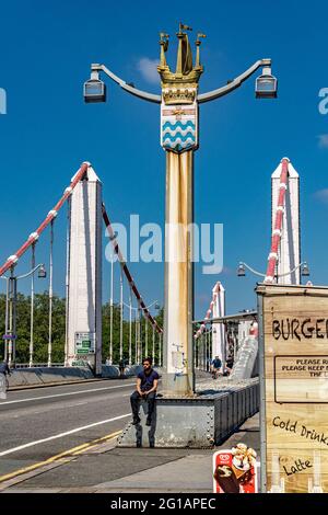 Un homme assis sur le Chelsea Bridge qui a ouvert en 1935 sur la Tamise reliant Chelsea sur la rive nord à Battersea sur la rive sud de Londres Banque D'Images