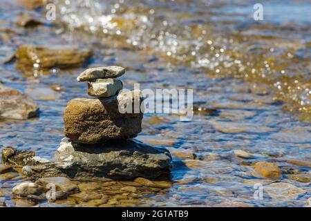 Les pierres sont équilibrées et empilées les unes sur les autres dans l'eau peu profonde d'une plage rocheuse au bord d'une rivière. Banque D'Images