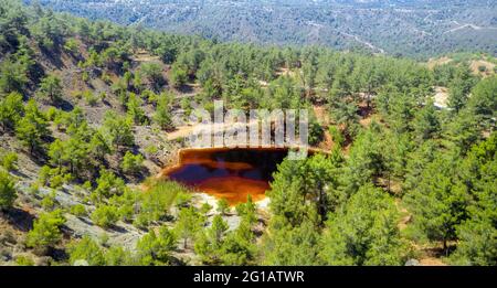 Restauration de la forêt dans une fosse minière d'opencast abandonnée près de Kinousa, Chypre. Vue aérienne du cratère de la mine de cuivre et du lac rouge Banque D'Images