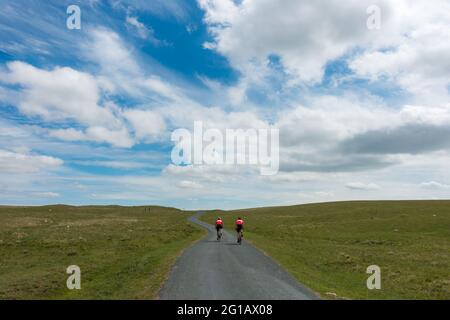 Paysages du Royaume-Uni : deux cyclistes vêtu de vélo rouge à travers Malham Moor, dans le parc national de Yorkshire Dales, lors d'une superbe journée d'été. Banque D'Images