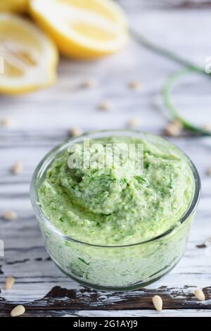 Pesto à l'ail Scape avec des ingrédients frais maison de citrons et de pignons sur une table en bois rustique blanc. Mise au point sélective avec un premier plan flou Banque D'Images
