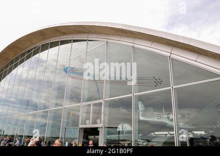 L'équipe d'exposition des flèches rouges de la Royal Air Force se reflète dans la vitre du musée de l'air américain de Duxford, au Royaume-Uni. Les avions à réaction RAF traînant de la fumée au spectacle Banque D'Images