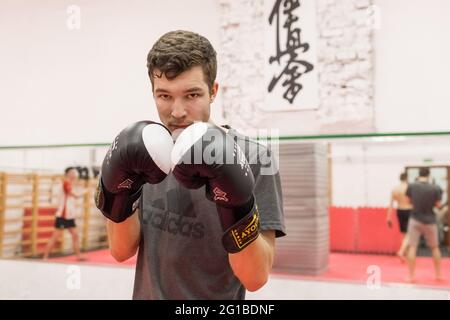 Belarus, Minsk - 07 mars 2020 : jeune homme sportif en gants de boxe sur le fond de la salle de sport. Banque D'Images