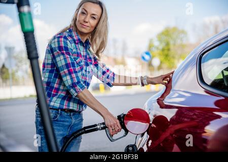 Une femme à une station-service pour faire le plein. Concept de départ, voyage. Banque D'Images