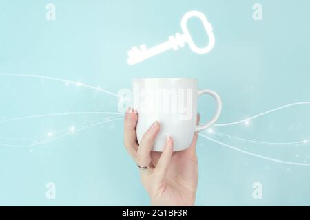 Touche succès. Vue rognée de la main féminine avec une tasse à café blanche et un signe clé icône de mot-clé sur fond bleu Banque D'Images