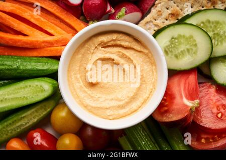 Bol avec vue sur le dessus de houmous faits maison servi sur une assiette avec un assortiment de légumes frais colorés Banque D'Images