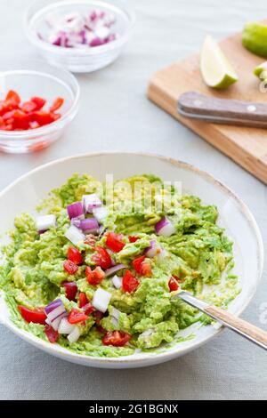 Du dessus de guacamole savoureux avec des tranches d'oignon rouge frais dans un bol en céramique sur la table Banque D'Images