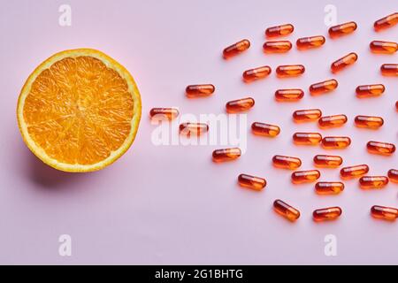 Vue de dessus composition d'oranges mûres coupées disposées sur une surface rose près des pilules dispersées dans un studio lumineux Banque D'Images