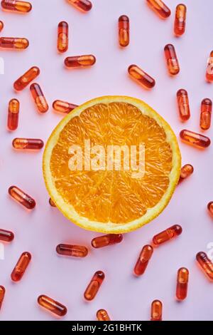 Vue de dessus composition d'oranges mûres coupées disposées sur une surface rose près des pilules dispersées dans un studio lumineux Banque D'Images