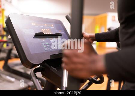Vue de côté de Crop anonyme African American sportif faisant de l'entraînement cardio sur machine elliptique dans la salle de gym moderne Banque D'Images