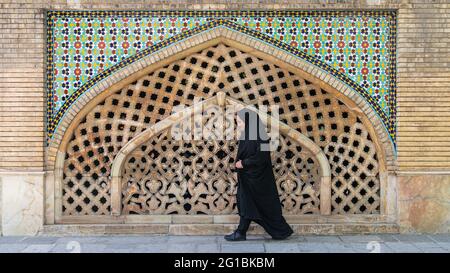 Téhéran, Iran - Mai 2019 : une femme iranienne se promenant devant une fenêtre artistique islamique dans le palais de Golestan Banque D'Images