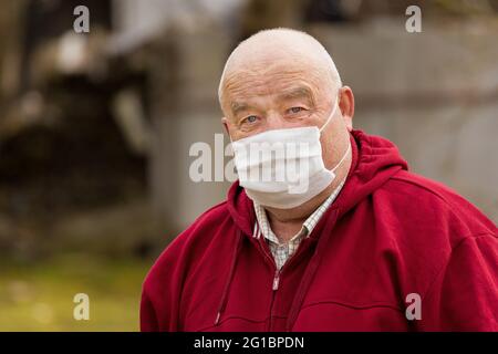 Portrait d'un homme européen âgé avec une courte coupe de cheveux dans un masque médical sûr et protecteur, gros plan. Banque D'Images