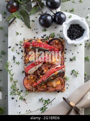 Sardine à l'huile d'olive, toast aux tomates noires et aux herbes sur un plateau en marbre Banque D'Images