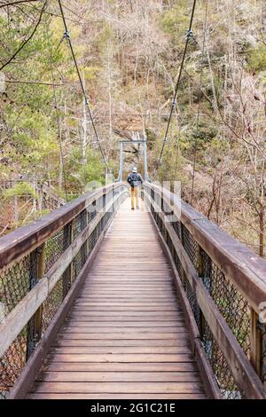 Mountaineer marchant sur un pont suspendu en bois dans la forêt Banque D'Images