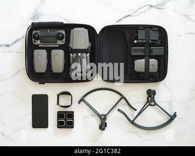 Drone pliant. Équipement de drone avec jeu complet sur fond de marbre blanc. Style minimaliste. Vue de dessus. Pose à plat. Kit de drone UAV en étui et accessoires. Concept d'équipement de tournage Banque D'Images