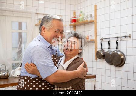 Un grand-père asiatique se fait huer et souriait avec grand-mère pendant la cuisson cuisine Banque D'Images