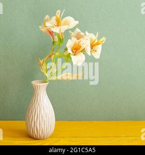 Vase de fleurs jaunes Alstroemeria sur table en bois. Fond vert Banque D'Images