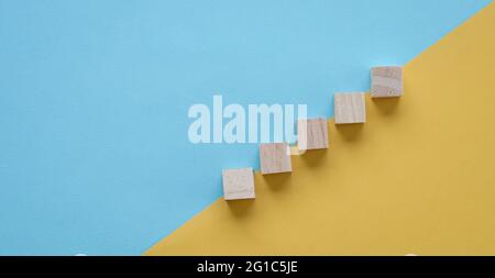 Bloc de bois empilé comme escalier. Sur fond bleu et jaune. Concept d'entreprise pour le processus de réussite de la croissance. Banque D'Images