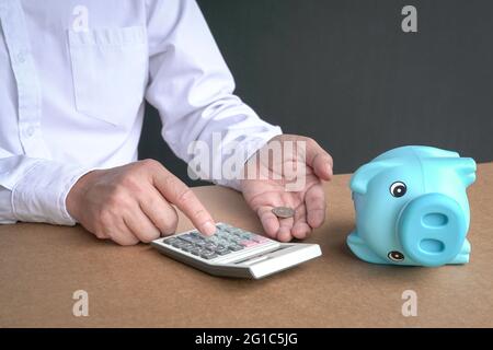 Homme d'affaires utilisant une calculatrice avec piggybank vide et une pièce de monnaie laissée sur la table. Concept de crise financière et de rupture. Banque D'Images