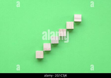 Bloc de bois empilé comme escalier. Sur fond vert. Concept d'entreprise pour le processus de réussite de la croissance. Banque D'Images