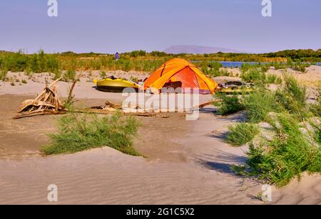 Camp touristique avec une tente et des bateaux à proximité immédiate de la rivière dans la zone semi-désertique; concept de voyage et de tourisme Banque D'Images