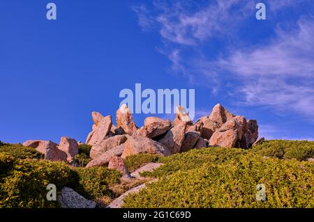 Formations rocheuses exquises parmi les buissons de genévrier sur un fond de ciel bleu avec des nuages Banque D'Images