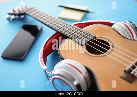 Casque guitare en bois et smartphone sur fond bleu Banque D'Images