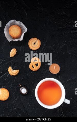 Biscuits au beurre danois avec thé, tiré du haut sur un fond noir avec un endroit pour le texte Banque D'Images