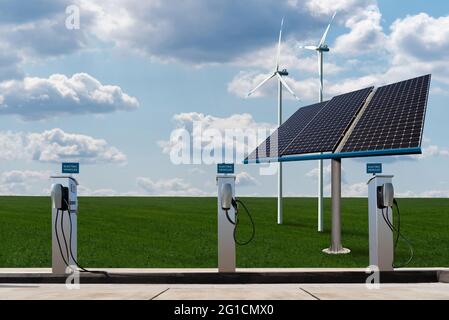 Postes de charge pour véhicules électriques sur fond de panneaux solaires et d'éoliennes Banque D'Images