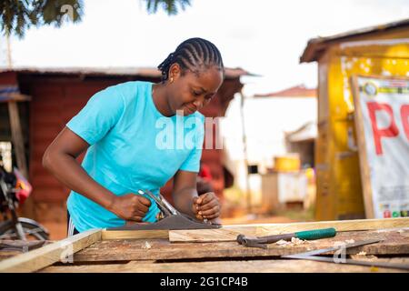 femme africaine utilisant un avion de cric pour habiller le bois dans la taille Banque D'Images