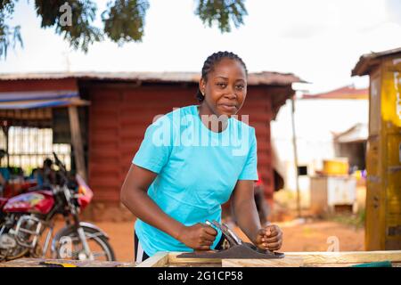 femme africaine utilisant un avion de cric pour habiller le bois dans la taille Banque D'Images