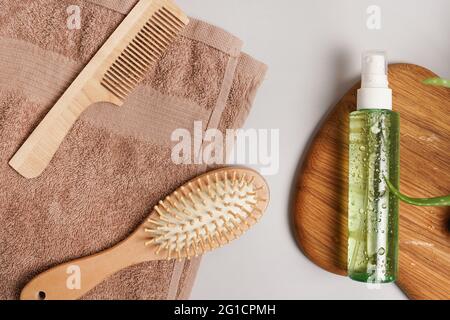 Produits pour le soin quotidien des cheveux. Peigne, shampooing ou lotion, serviette sur fond gris vue du dessus Banque D'Images
