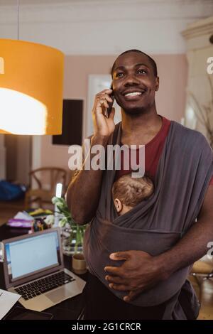 Homme d'affaires souriant parlant sur smartphone à la maison Banque D'Images