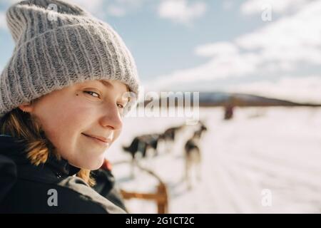 Portrait d'une adolescente portant un chapeau en tricot faisant du traîneau à chiens pendant l'hiver Banque D'Images