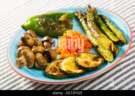 Assortiment de délicieux légumes biologiques grillés servis sur une plaque en céramique bleue. Banque D'Images