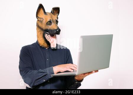 personne avec un masque de chien dactylographiant sur un ordinateur portable sur fond blanc, concept de technologie et de communication Banque D'Images