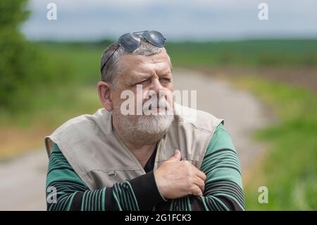 Joli portrait extérieur de l'homme âgé caucasien barbu portant des lunettes de soleil noires sur la tête et regardant vers l'avant Banque D'Images
