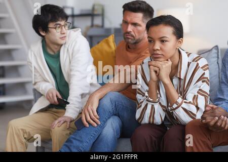 Portrait d'une jeune femme afro-américaine regardant la télévision à la maison avec des amis, espace de copie Banque D'Images